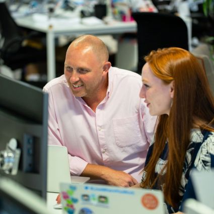 two researchers sitting at a table looking at laptops